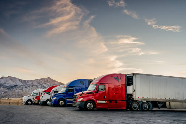 A line of powerful semi-trucks parked against the breathtaking backdrop of mountains and sky, representing the vital role of fleet trade associations for fleet owners and operators in the trucking industry